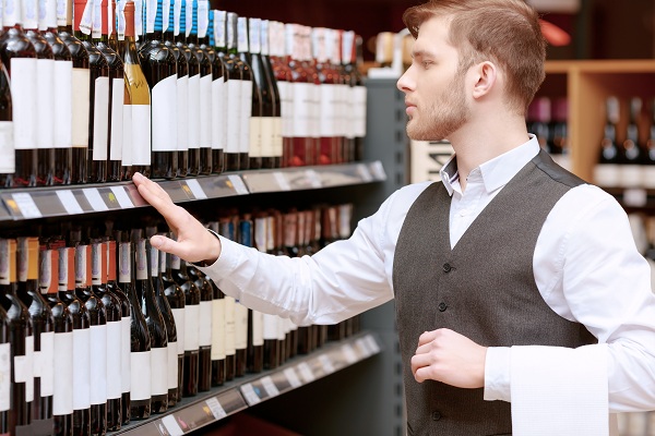 Sommelier in the store near shelves liquor pos