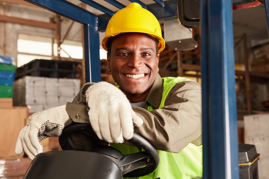 African logistics man as a forklift driver in the warehouse of a
