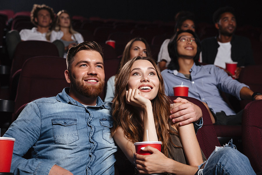 Feliz pareja joven sentada en el cine y disfruta viendo la película