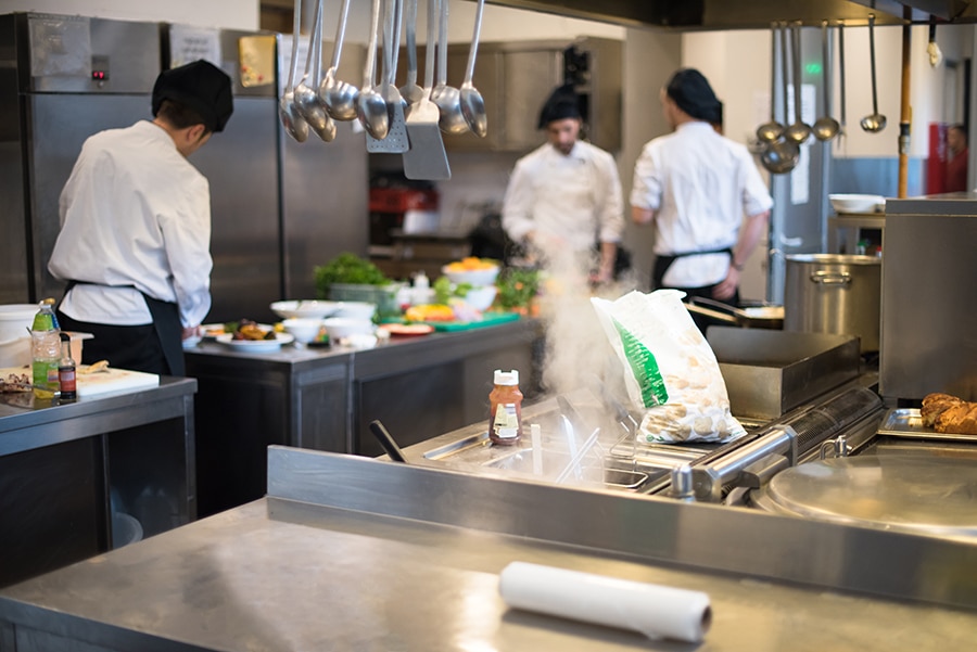 Professional team cooks and chefs preparing meals at busy hotel or restaurant kitchen